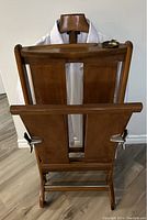 Front view of the wooden valet stand with a white dress shirt hanging on the contoured wooden hanger, showcasing the valet's slim profile and hanger design.