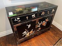 Overall perspective view of cabinet showing top, front, floral motifs and metal pulls
