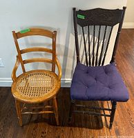 Photo of two wooden chairs side by side, one with woven cane seat and lighter wood, the other with carved dark wood back and blue cushion.