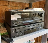 Stacked Pioneer stereo receiver model SX-251R on top of RCA five-disc CD changer player with remote and multiple CD cases on top