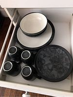 Drawer containing plates, bowls, and cups showing the full set minus one soup bowl.