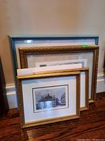 Group photo of 5 framed prints leaning against a wall, including three gold ornately carved frames and one blue frame.