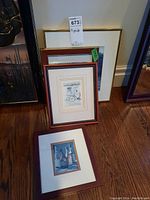 Four framed prints grouped on floor, different frames evident