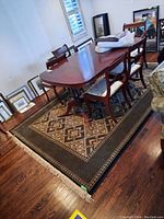 Full view of rectangular area rug under dining table with fringes and multi-patterned beige and black design.