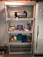 Front view of the plastic shelving unit with various stored items on some shelves to show size and build.
