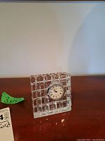 Square Waterford crystal clock with a clear grid crystal pattern and embedded clock face on wooden surface.
