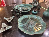 Multiple Blue Mountain Pottery pieces arranged on kitchen counter showing plates, deer candlesticks, holders, and candy dish.