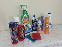 Full assortment of cleaning supplies including sprays, powders, bleach, and cleaning pads arranged against a plain wall.