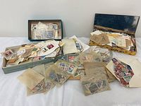 Wide view showing multiple boxes and loose stacks of assorted stamps and envelopes spread out on a flat surface.