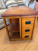 Side view showing three vertically stacked drawers with black metal handles and adjacent open cabinet space.