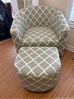 Front view of gray and off-white patterned bucket chair with matching stool in front on wood floor