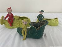 Three elf ceramic figurines on shoe and boot-shaped planters in yellow and green colors.