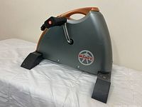 Side view of the Marcy exercise bike showing gray and copper-tone plastic casing with brand logo and pedal with straps.