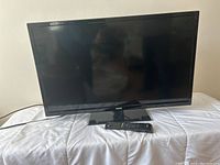 Front view of the 34 inch RCA television showing black bezel and screen on a stand base, placed on white surface.