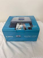 Closed original box of the Canon Selphy CP510 compact photo printer with printed photo output shown on the box.