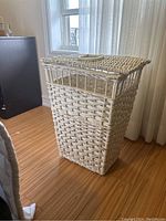 Side view of tall white wicker basket showing woven texture and hinged lid