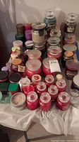 Wide view of assorted candles showing large and small jar candles, pillar candles, and votives in various colors including red, pink, green, purple, brown, and white.