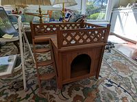 Side angle view of wooden cat house showing ladder and lattice railings on rooftop deck.