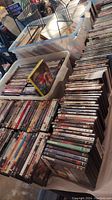 Wide angle photo showing large containers and stacks of DVDs in plastic bins and on tables
