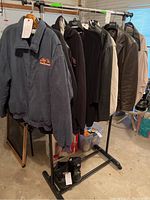 Full rack view of jackets and boots including fabric and leather jackets, and overshoes on the floor.