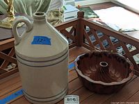 Stoneware jug and bundt pan placed on a wooden lattice table, showing size and condition.