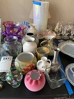 Wide view of grouped vases and pottery showing various shapes, colors, and designs including tall white vase, painted glass, and crystal.