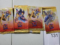 Photo of four unopened 1995 Fleer Ultra X-Men promotional packs with prominent character artwork including Storm, Wolverine, and Cable.