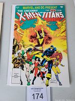 Front cover of the comic book showing The Uncanny X-Men and The New Teen Titans characters in colorful action poses with Marvel and DC logos.