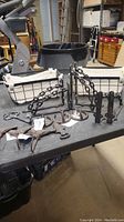 Overall lot showing two wire baskets and cast iron pieces on table in workshop setting