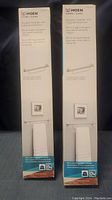 Photo of two boxed Moen Home Care towel bars with packaging showing product information and branding