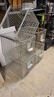 Stacked five steel wire mesh bins showing front metal label plates and open wire grid sides.