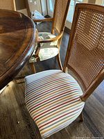 Close-up of a cane back dining chair with striped fabric seat and wooden frame near a wooden dining table corner
