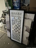 Vertical geometric black and white art print, framed in black, showing repeated pattern shapes