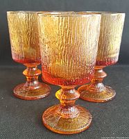 Four amber textured glass goblets grouped together showing texture and design