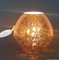 Copper tone glass light fixture illuminated showing speckled glow effect on glass.