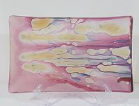 Front view of rectangular tray showing abstract color pattern in pink, yellow, purple, and white with clear acrylic stands.