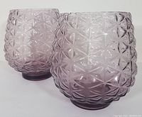 Front view of two purple hand blown glass items with diamond textured pattern, showing shape and footed base