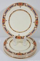 Top view of the set of five side plates showing the detailed Art Deco orange flower and blue geometric border pattern on cream background.