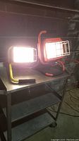 Two halogen flood lights turned on, placed on metal cart.