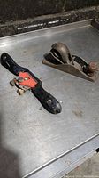 Woodworking block plane and card scraper on metal surface