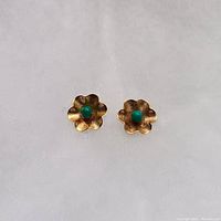Front view of pair of gold flower earrings with turquoise centers on white background