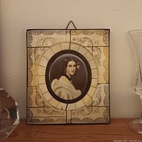 Front view of oval handpainted portrait of woman with decorative tiled frame.