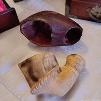 Antique meerschaum pipe shown with original fitted leather case, pipe lying on its side showcasing carved ridges and smooth mouthpiece