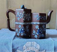Side view of conjoined Yixing teapot showing blue floral decorations and hexagonal shape