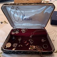Overview of jewelry box interior showing assorted earrings, pendants, charms and ring