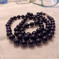 Close-up of dark blue lapis lazuli beads showing smooth polished surfaces and spherical shape.