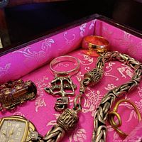 Close-up photo highlighting the watch, small train charm, silver bracelet, and anchor pendant with textured links