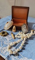 Mixed lot of vintage shell, stone, and bone jewelry pieces laid out on fabric with the wooden box opened in the background, showing all items included.