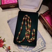 Necklace displayed laying flat in green velvet box showing full length and bead color.