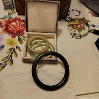 Image showing two jade bracelets and one green jade beaded necklace in a jewelry box.